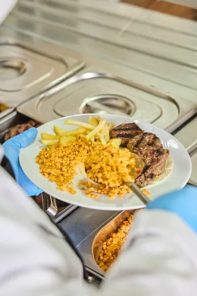 Sıcak servis hattında porsiyonlanan köfte, bulgur pilavı ve patates