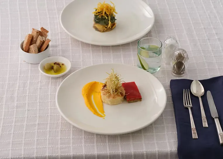 Kurulu masada porsiyonlanmış tabak sunumu, ekmek sepeti ve bardak